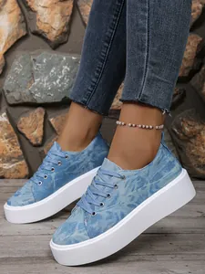 Close-up van blauwe denim platform sneakers met dikke witte zool en vetersluiting