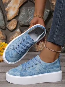 Detail van casual platform sneakers van denim voor dames met veters en dikke witte zool