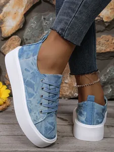 Gedetailleerde weergave van blauwe denim platformsneakers voor dames met witte dikke zolen.