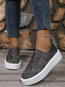 Close-up van casual denim sneakers met een dikke witte zool en een glanzende grijze afwerking