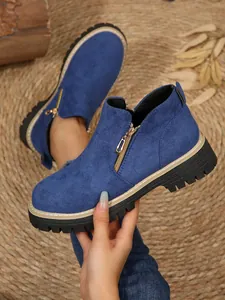 Détail de bottines bleues à bout rond dotées d'une fermeture éclair dorée sur le côté