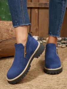 Détail de bottines en daim bleu avec fermeture éclair dorée latérale et semelle crantée