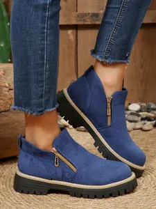 Détail de bottines en daim bleu avec fermeture éclair latérale et semelle épaisse