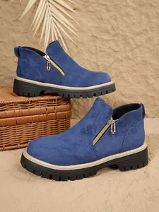 Détail de bottines Martin en daim bleu avec fermetures éclair et semelles crantées.