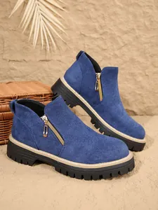 Gros plan sur des bottines en daim bleu montrant la fermeture éclair dorée et la semelle