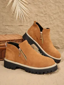 Vue détaillée de bottines en daim marron avec fermeture éclair dorée et semelle plateforme noire.