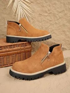 Gros plan de bottines en daim marron avec fermetures éclair dans un décor rustique