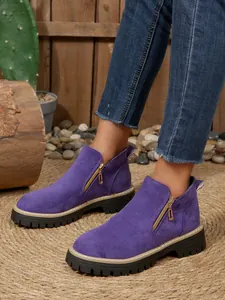 Vue détaillée des bottines en daim violet avec fermetures éclair dorées et semelles noires.
