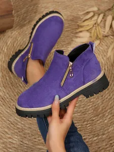 Gros plan de bottines en daim violet avec fermeture éclair latérale et semelle plateforme.