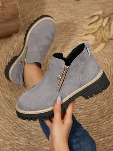Zoom sur des bottines en daim gris avec fermeture éclair latérale et semelles épaisses