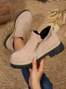 Détail des bottines Martin en daim beige pour femmes avec fermeture éclair et semelle crantée.