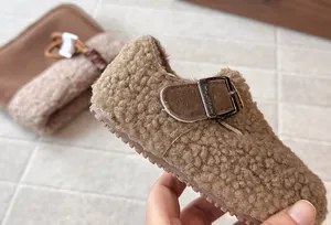 Κοντινό πλάνο παιδικών παπουτσιών Birkenstock με καφέ γούνινη υφή και μεταλλική αγκράφα