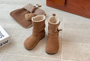 Detail of girls' brown suede winter boots with warm faux fur lining and buckle straps