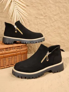Vue détaillée de bottines élégantes en daim noir avec fermeture éclair dorée et semelle crantée