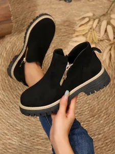 Vue détaillée de bottines en daim noir avec fermeture éclair latérale dorée et semelle crantée