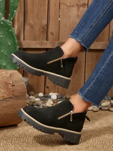 Détail de bottines noires en daim avec fermeture éclair dorée et semelle épaisse crantée