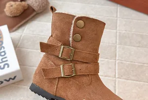 Close-up of brown suede girls' winter boots with metal buckles and warm fleece lining.
