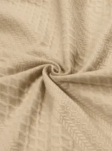Detailed view of beige jacquard knit fabric showing intricate textured patterns