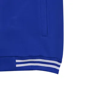 Macro view showing the ribbed hem detail of a blue baseball jacket with white stripes.
