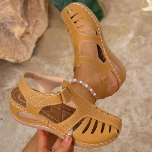 Detail view of tan wedge sandals featuring hollow-out design and white stitching.