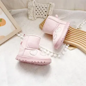 Detail view of pink girl's snow boots with heart embroidery and back bow accents