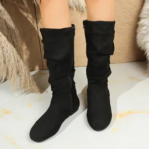 Detail showing the slouchy suede texture and side zipper of black mid-calf boots.