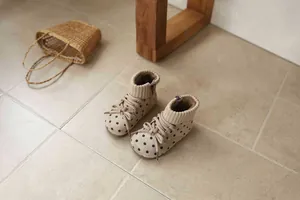 Detailed view of girls' beige polka dot winter boots with knit collar and warm lining