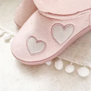 Close-up detail of silver heart embroidery on soft pink girl's winter snow boots