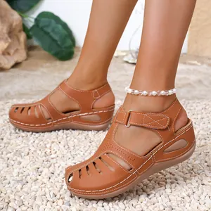 Close-up of brown leather wedge sandals with white stitching and cut-out design.