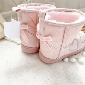 Close-up detail of pink toddler girl snow boots with plush lining and decorative back bows.