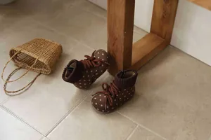 Close-up detail of toddler girl's retro brown polka dot winter boots with knitted cuffs