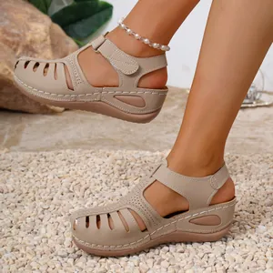 Detailed close-up view of khaki wedge sandals with hollow closed-toe and white stitching.
