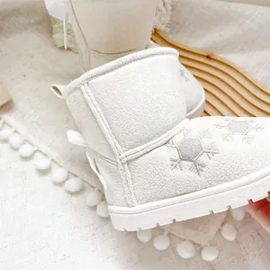Detailed view of white kids' snow boots with snowflake embroidery and lovely heel bow
