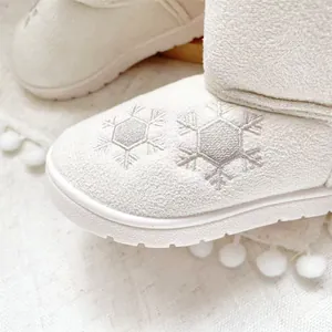 Close-up of silver snowflake embroidery on cream winter girls' snow boots