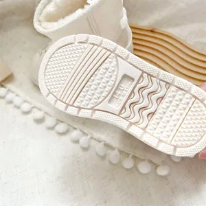 Close-up showing the textured anti-slip rubber sole of a cream baby winter snow boot