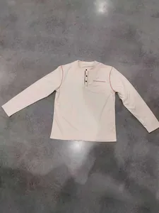 Vue détaillée d'un t-shirt Henley beige à manches longues posé à plat sur un sol gris