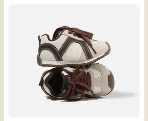 Detailed side view of toddler soft-sole sneakers featuring brown laces and zigzag stitching