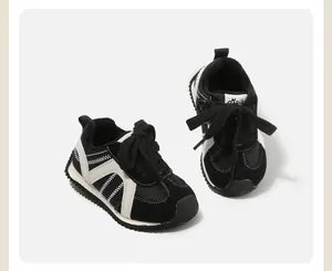 Detail view of black and white infant sneakers with contrast zig-zag stitching and laces.