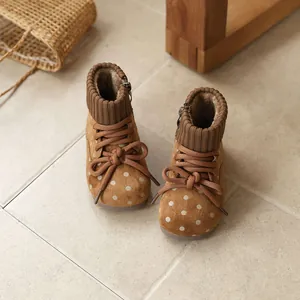 Vintage girls' winter boots with polka dots and warm knit collar displayed on tile floor