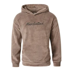 Close-up detail of cozy brown plush hoodie featuring black Muscleattack script embroidery.