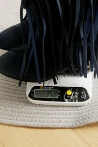 Close-up showing the 758g weight of a blue suede fringe cowboy boot on a digital scale