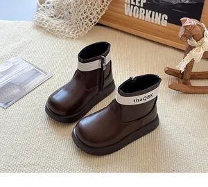 Gros plan de bottines Chelsea vintage pour enfants marron avec détail de sangle blanche