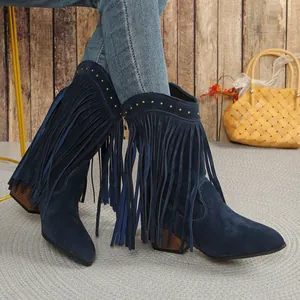 Close-up detail of navy blue suede western boots with long fringe and gold studs.