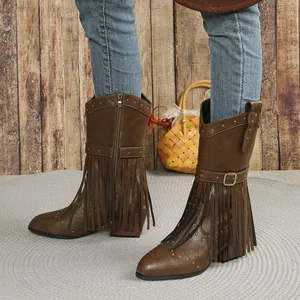 Close-up of brown western cowboy boots with fringe and metal studs.