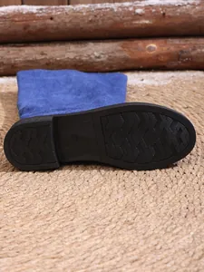 Close-up of non-slip rubber sole detail on blue suede high-top fashion boots.