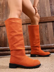 Side view detail of vibrant orange suede knee-high boots with durable low black heel