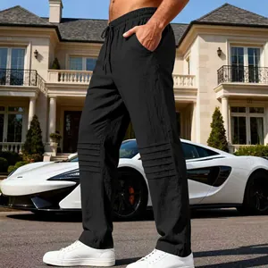 Détail latéral du pantalon en lin noir pour homme avec des plis stylés aux genoux.