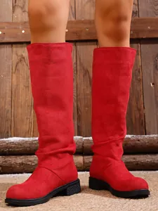 Close-up detail of stylish red suede knee-high boots with low square heel and rubber sole