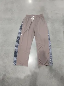 Men's streetwear brown straight-leg trousers with paisley side panels and snap buttons.