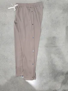 Detail view of brown hip-hop straight leg pants with side metal snap buttons and drawstring.
